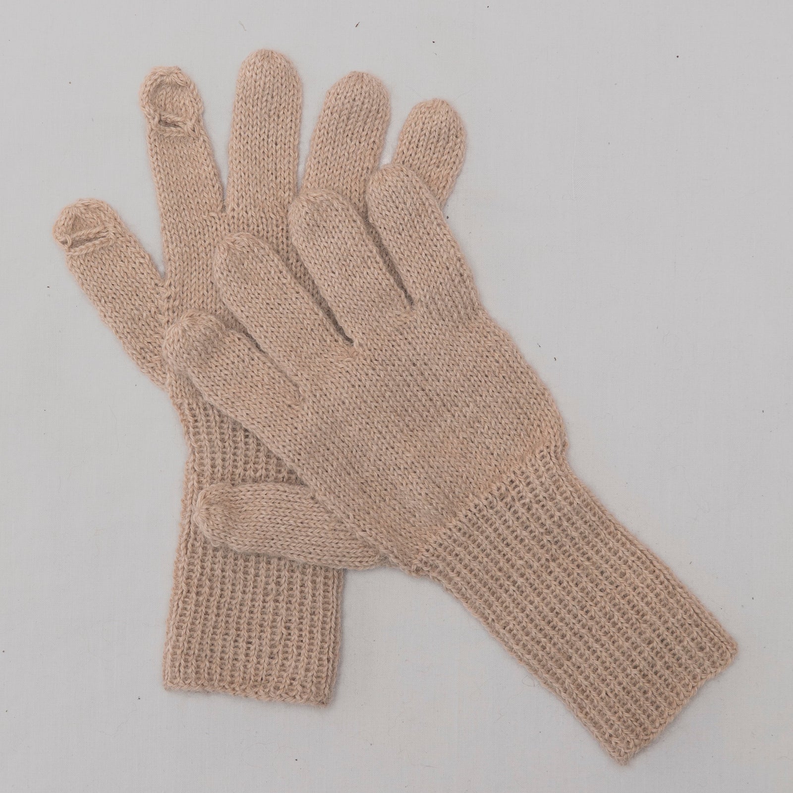 A pair of light beige knit gloves with ribbed cuffs,