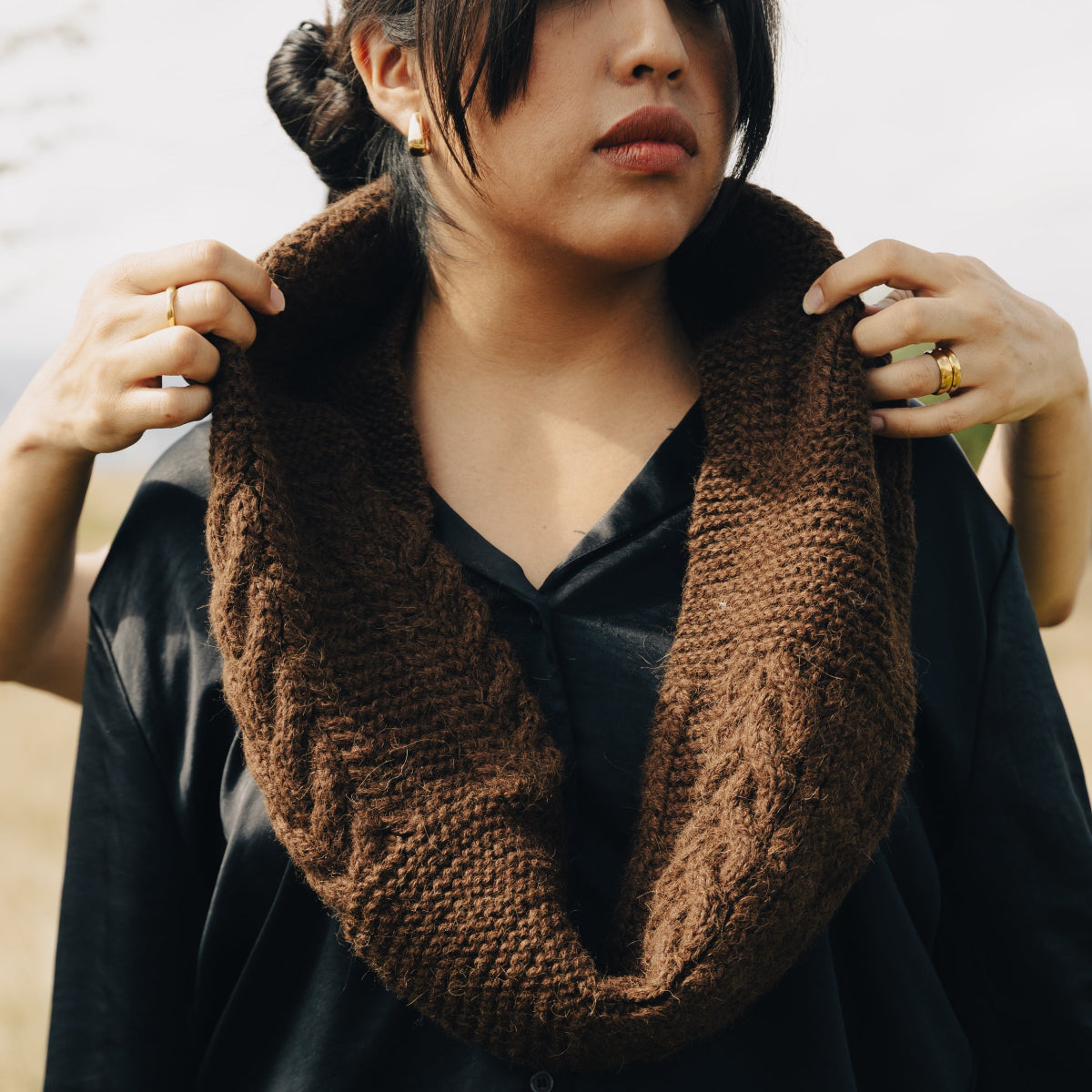 A woman wearing a thick, chunky brown cable-knit cowl neck warmer.