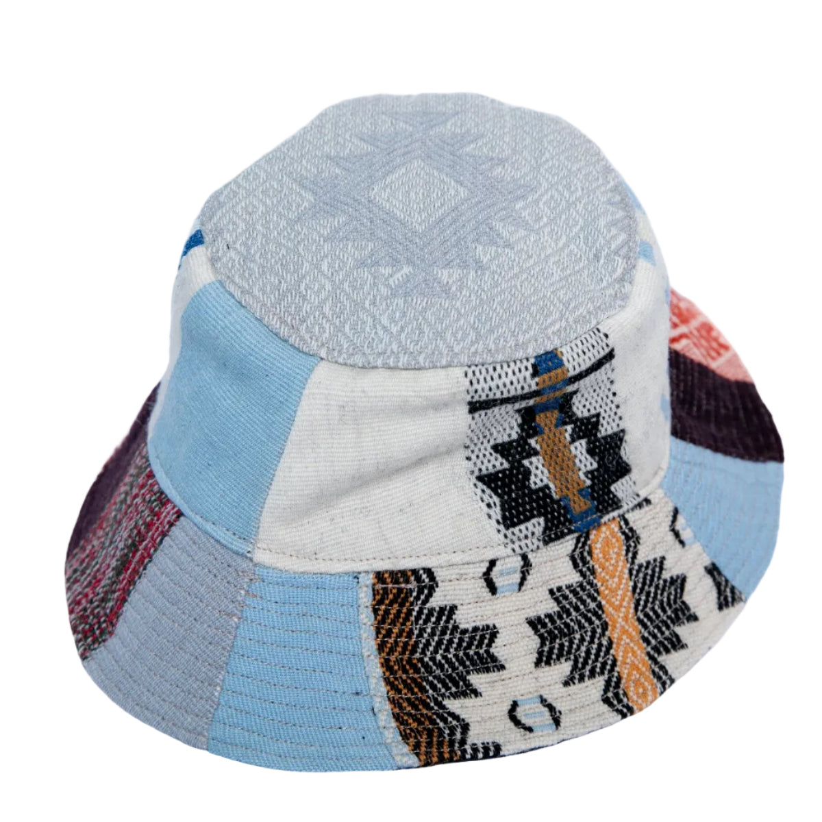 A patchwork bucket hat made from various woven textile panels in light blue, gray, beige, black, and brown, featuring geometric patterns.